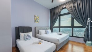 Ett hotellrum med två sängar, ett stort fönster med gardiner, en takfläkt och utsikt över stadsbilden.