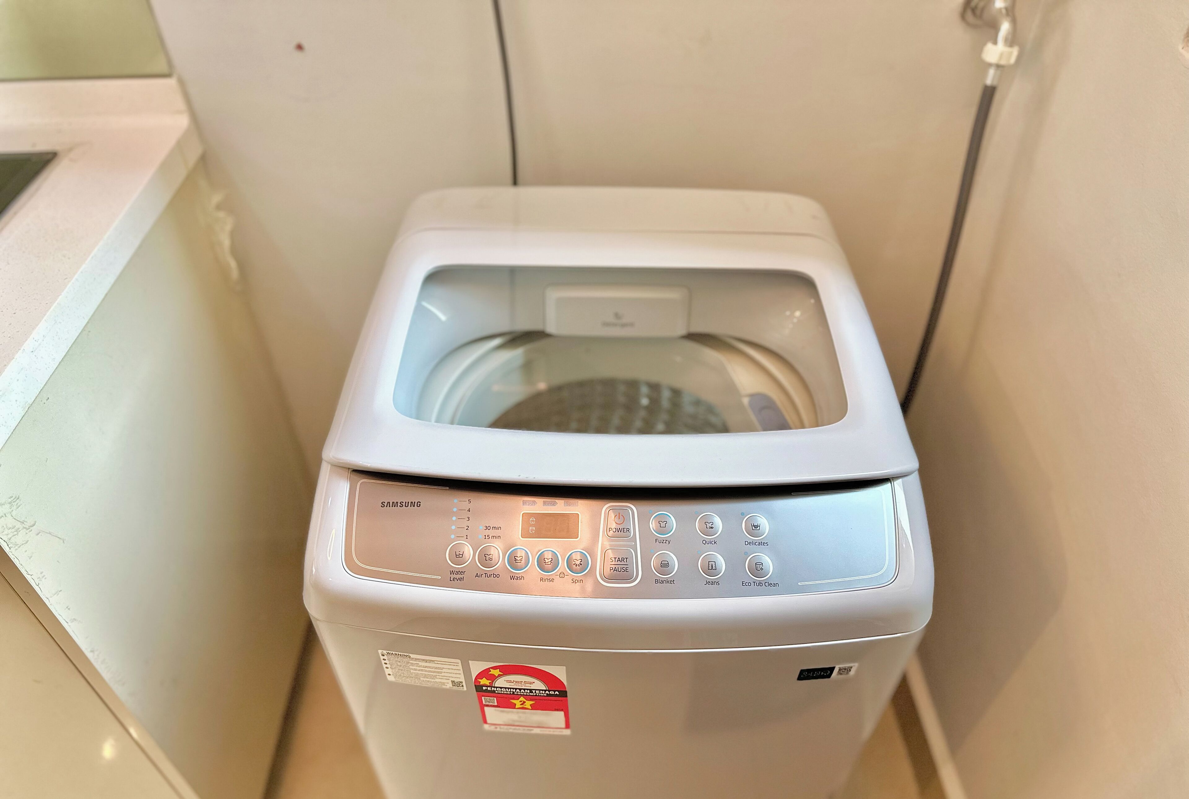 A compact, white washing machine with a digital display and multiple control buttons.