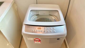 A compact, white washing machine with a digital display and multiple control buttons.