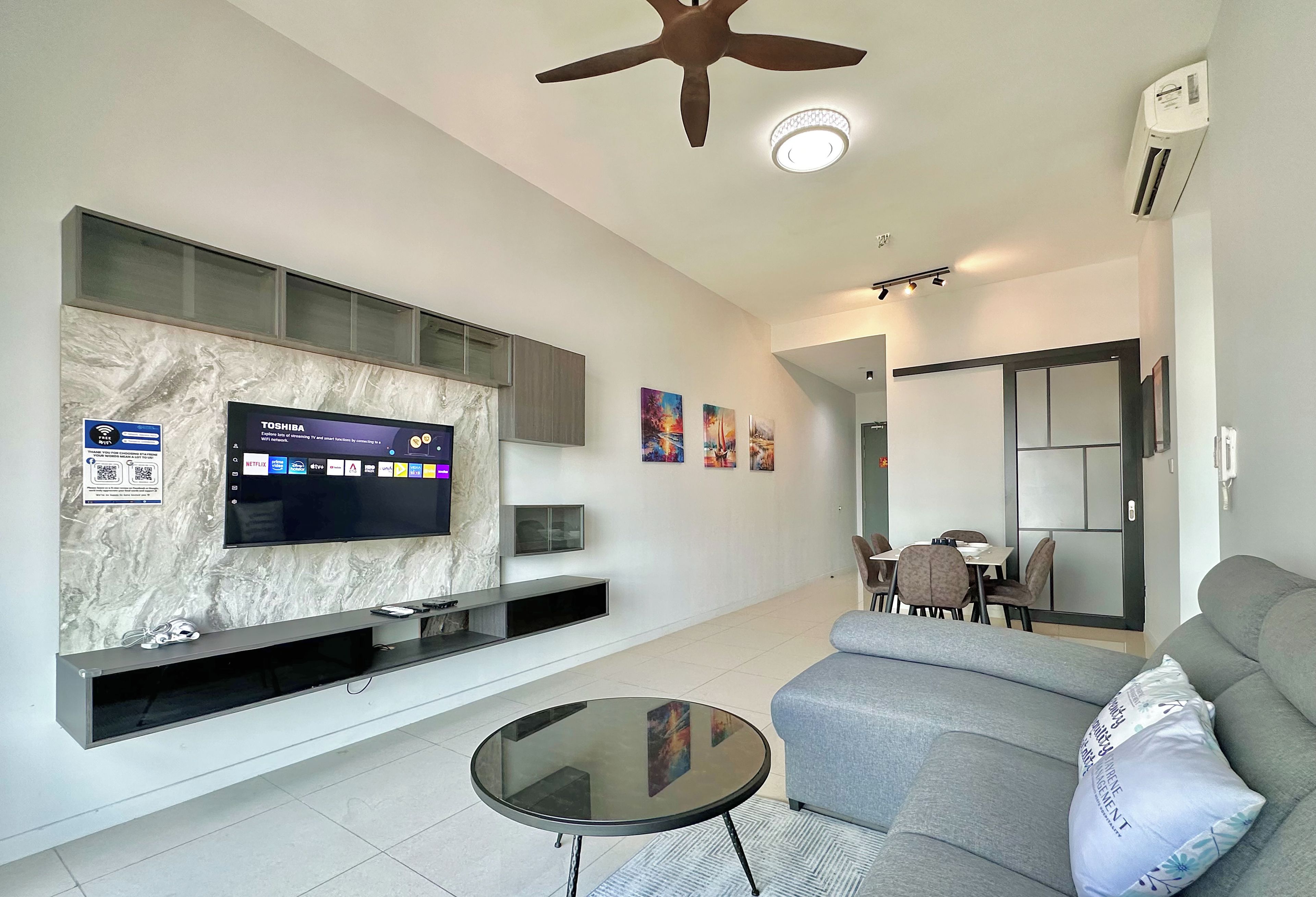 Ein modernes Wohnzimmer mit Flachbildfernseher, Deckenventilator und Essbereich mit Tisch und Stühlen.