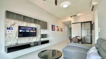 A modern living room with a flat-screen TV, a ceiling fan, and a dining area with a table and chairs.
