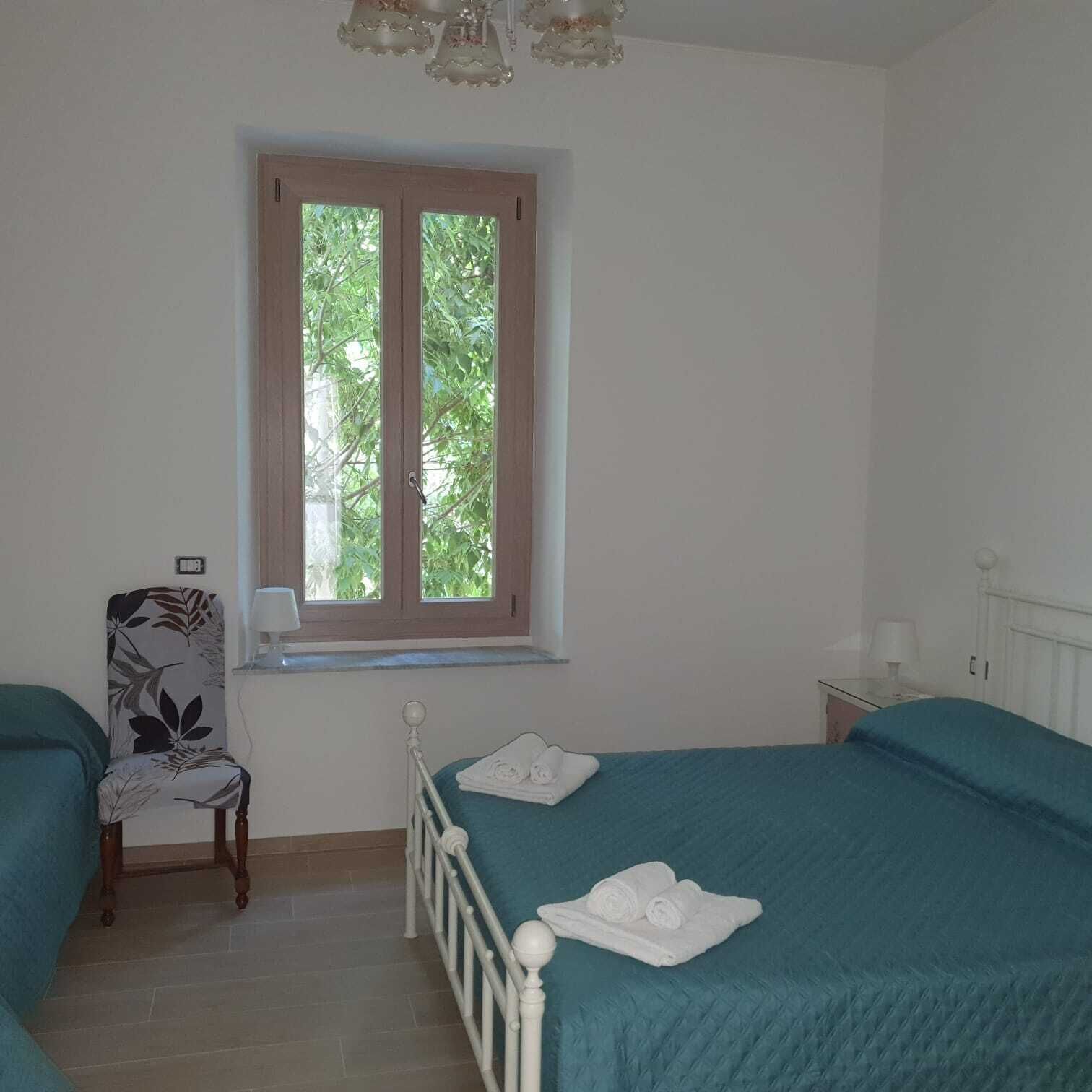 Een slaapkamer met twee bedden, een raam, een stoel en een radiator.