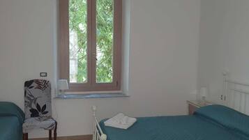 Een slaapkamer met twee bedden, een raam, een stoel en een radiator.