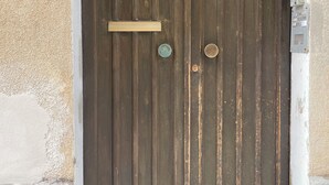 A double wooden door with a brass handle and a small brass plate above it. - Illy House in downtown Alghero. (Alghero)