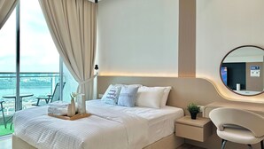 A modern hotel room with a large bed, bedside table, and a view of a cityscape through large windows. - Paragon Suites CIQ By Stayrene (Johor Bahru)