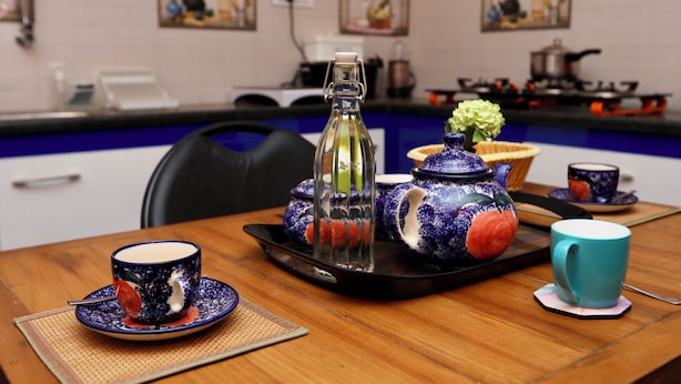 Uma mesa de jantar com um bule, xícaras e um suporte.