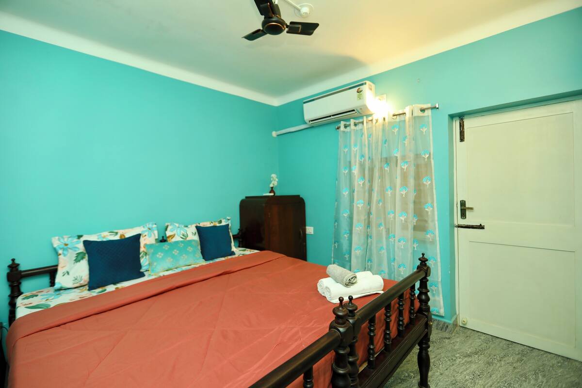 Un dormitorio con cama, ventilador de techo, aire acondicionado, armario y una puerta.