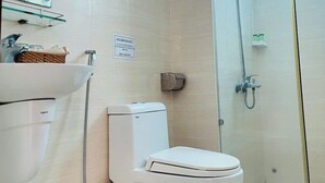 A modern bathroom with a toilet, sink, and glass-enclosed shower. - IU Beach Hotel Phu Quoc (Phu Quoc)