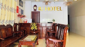 A hotel reception area with wooden furniture, a reception desk, and a ceiling fan. - IU Beach Hotel Phu Quoc (Phu Quoc)