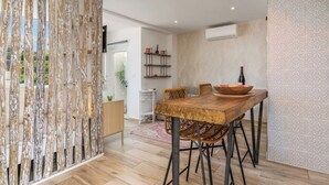 Een moderne eetruimte met een houten tafel, rieten stoelen en een decoratief wandpaneel.
