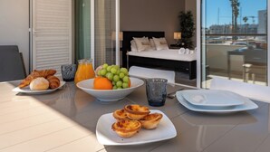 A breakfast table with croissants, a bowl of fruit, and a glass of orange juice.