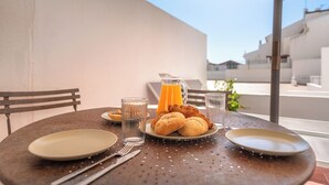 A table set for breakfast with croissants, a jug of orange juice, and a glass of water. - 1 bedroom apartment w/pool - Vilamoura Marina Center (Quarteira)