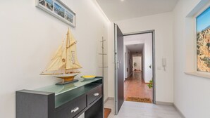 Un pasillo con un velero de juguete sobre una encimera, una puerta que da a otra habitación y un cuadro en la pared.