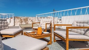 A rooftop terrace with outdoor seating, a table with a pitcher, and a clear view of the city skyline. - Cozy 1-bedroom house in the historic old town of Portimão. (Portimão)