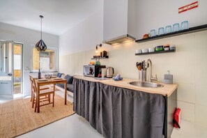 A compact kitchen with a dining area, a microwave, a kettle, and a sink.