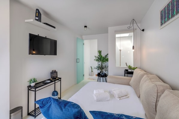 A modern bedroom with a bed, a TV, a plant, and a window.