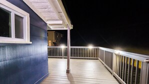 Une terrasse en bois dotée d’une rambarde, d’une fenêtre et d’une porte donnant sur un espace intérieur.