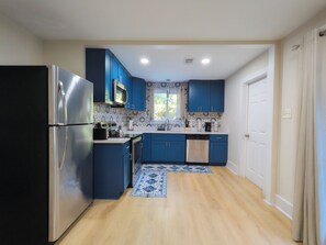 Una cocina moderna con armarios azules, electrodomésticos de acero inoxidable y un salpicadero con diseño.