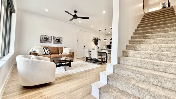 A modern living room with a sofa, a coffee table, and a staircase leading to an upper floor. - Luxury Kanab Retreat | Pool, Hot Tub Near Zion (Kanab)