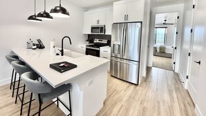 A modern kitchen with a central island, stainless steel appliances, and a minimalist design. - Luxury Kanab Retreat | Pool, Hot Tub Near Zion (Kanab)