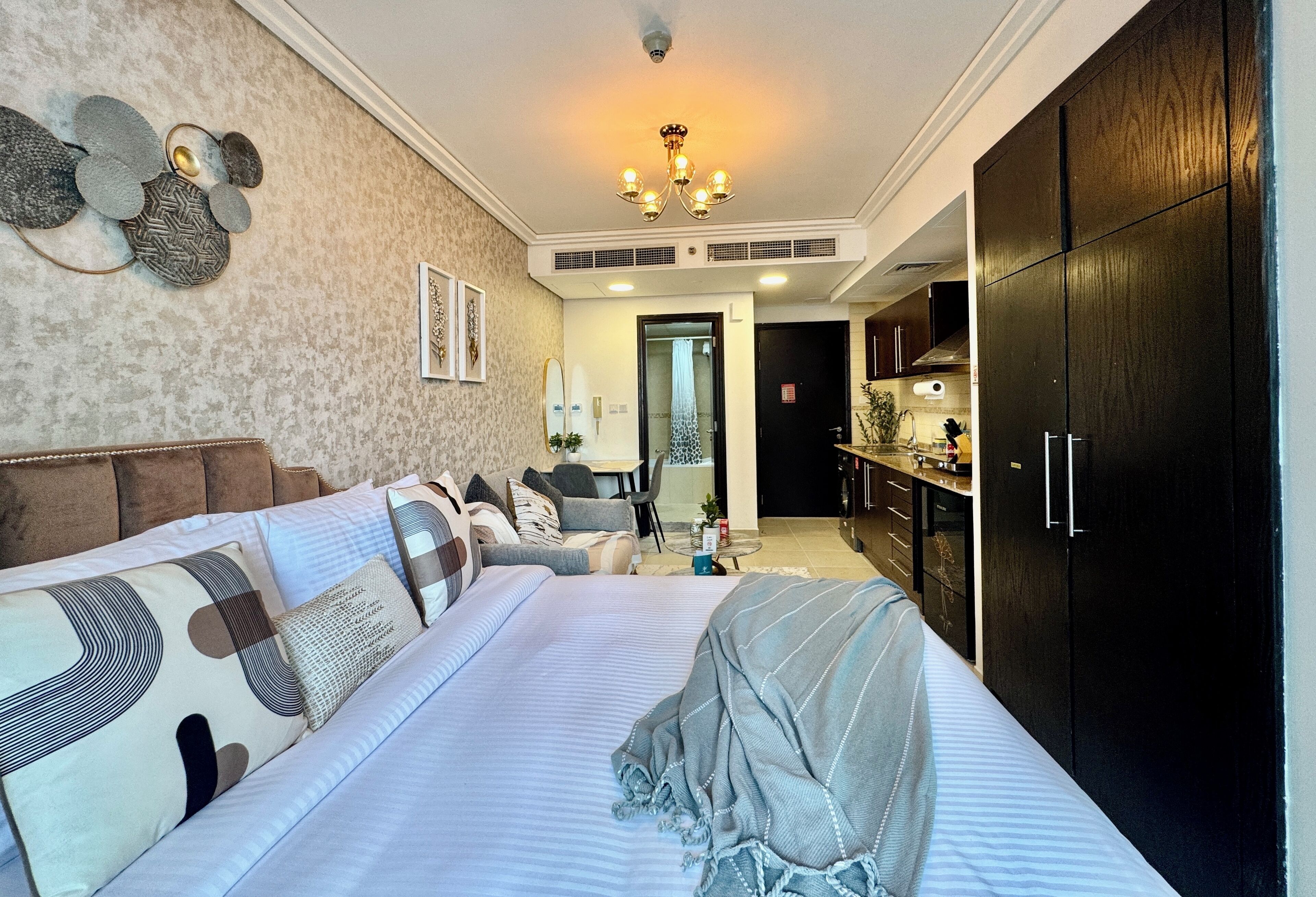Une chambre à coucher avec un grand lit, un canapé, un lustre et une armoire.