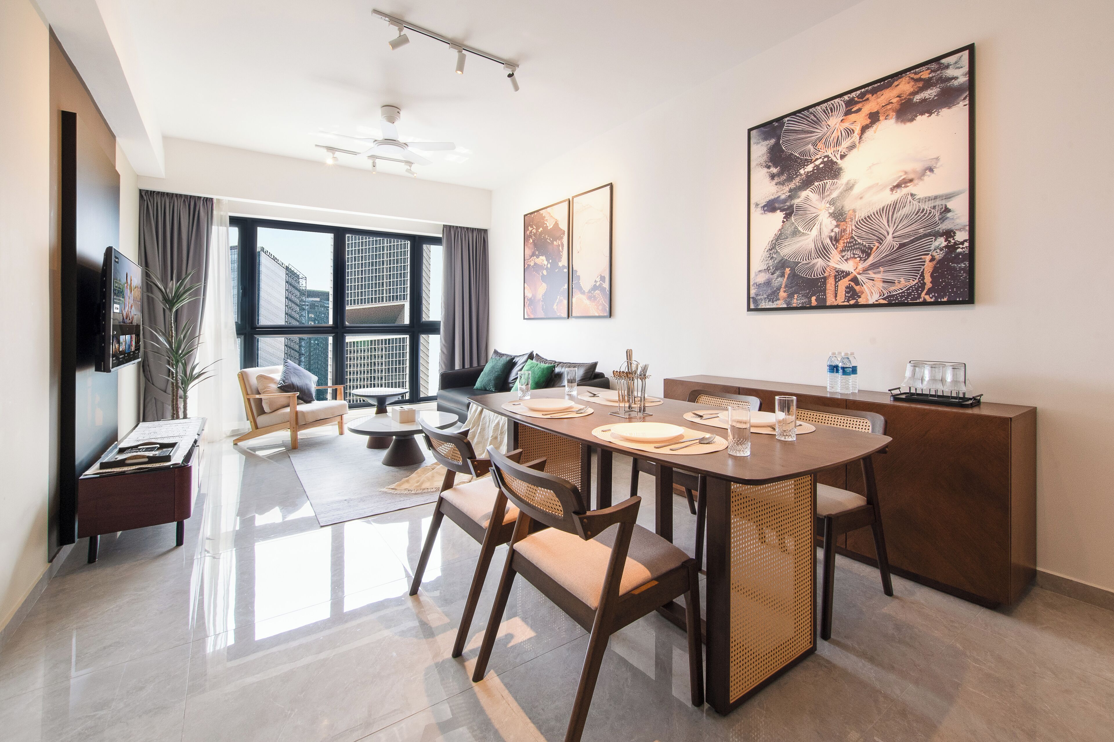 A modern living room with a dining area, large windows, and a flat-screen TV.