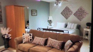 A living room with a brown sofa, a small table, a ceiling fan, and decorative wall art.