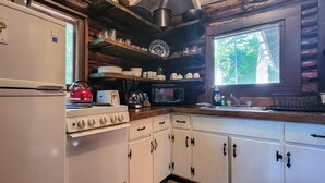 A kitchen with a refrigerator, stove, microwave, and wooden cabinets. - Escape to The Hideout, a charming 2-bedroom cabin in Boothbay Harbor. (Boothbay Harbor)