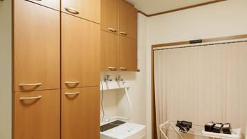 A compact room with wooden cabinets, a washing machine, and a drying rack.