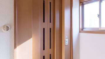 A wooden elevator door with a vent, a window to the right, and a light switch on the wall.
