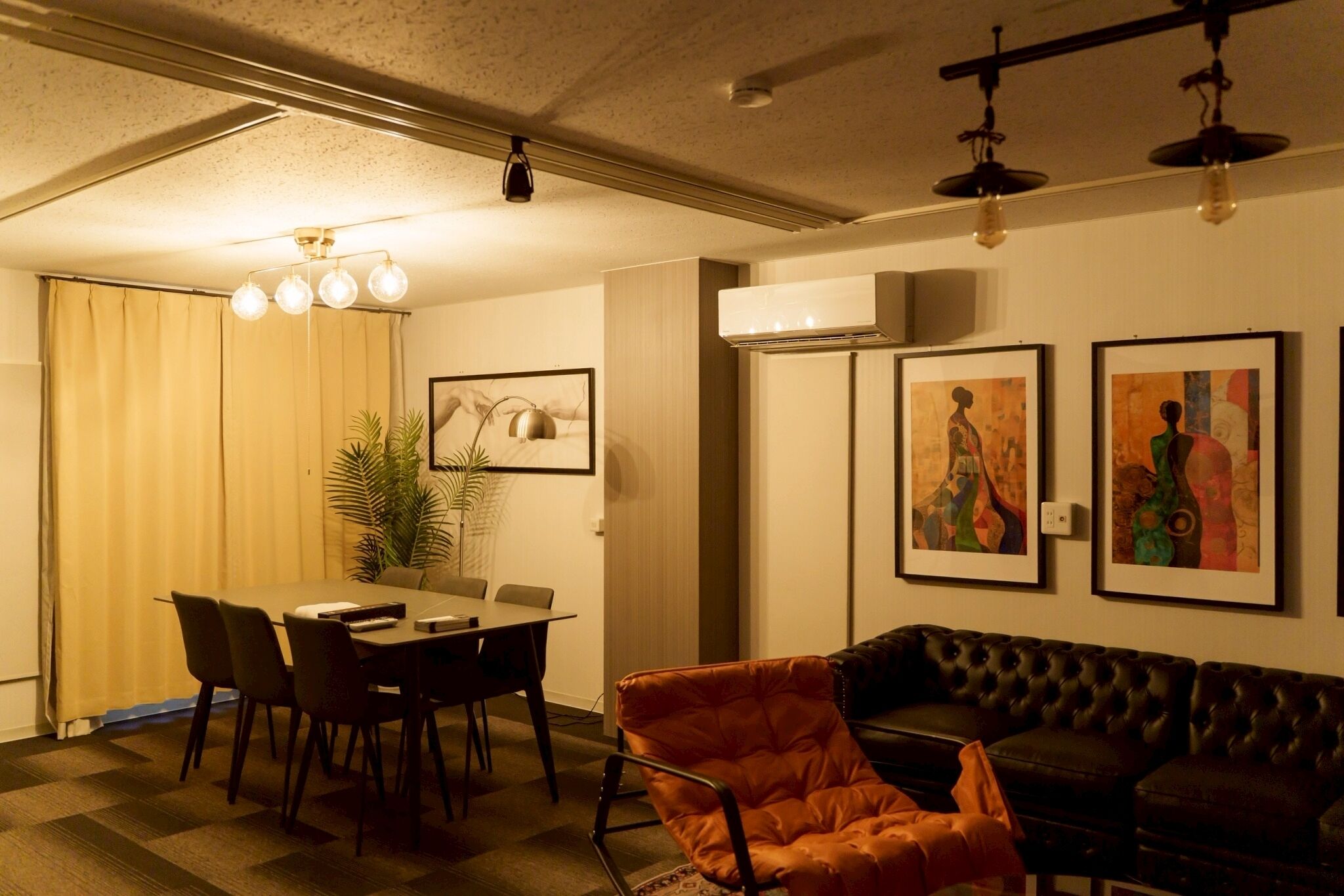 A dining area with a table and chairs, a sofa, and artwork on the walls.