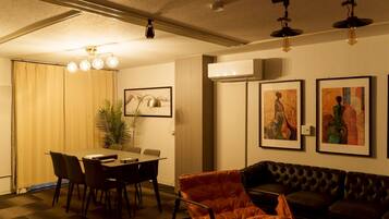 A dining area with a table and chairs, a sofa, and artwork on the walls.