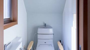 A small, narrow bathroom with a white toilet, a wooden-framed window, and a white sink.