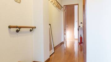 A hallway with a wooden bench, a fire extinguisher, and a door at the end.
