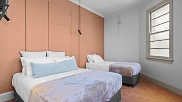 Una camera da letto con due letti, un'ampia finestra con persiane e una lampada a sospensione.