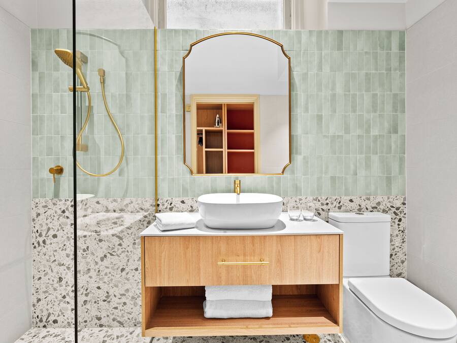 A bathroom with a freestanding shower, a sink with a gold faucet, and a toilet.