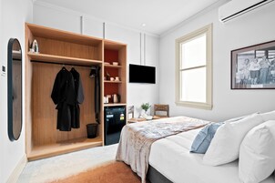 Un dormitorio con cama, armario, televisor y ventana.