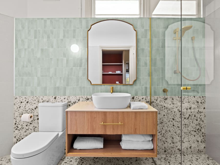 A bathroom with a freestanding toilet, a sink with a mirror above it, and a shower area.