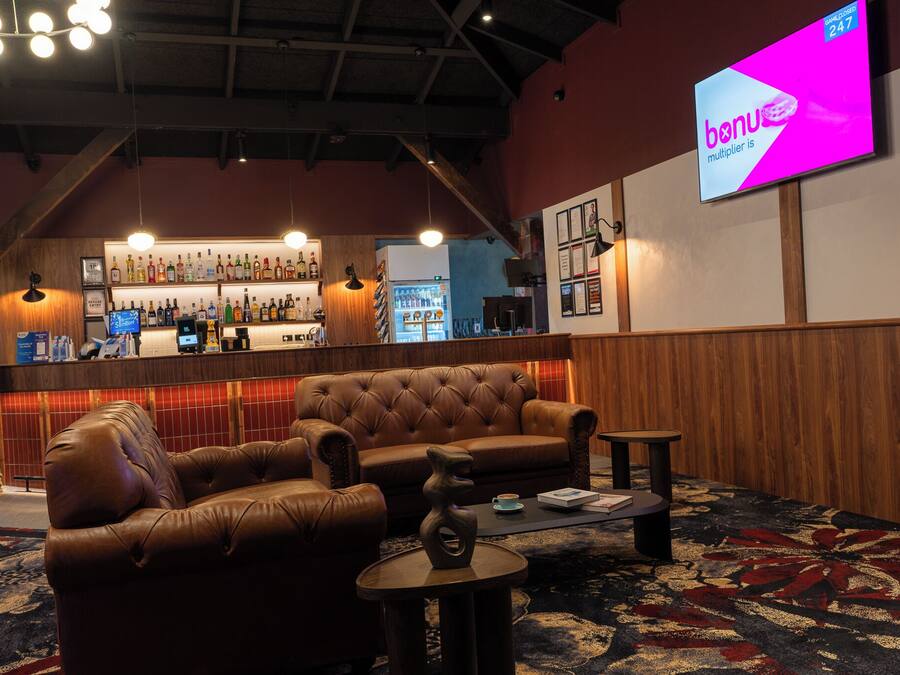 A bar area with a leather sofa, a coffee table, and a television screen displaying 'banus multiplier is'.