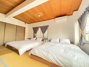 A room with two beds, a wooden ceiling, and a window with curtains. - Huge facility with 4 floors for rent / BBQ available anytime / 1 station to Namba station / 14 bedrooms / 28 beds / Sleeps up to 42 people (Osaka city, Nishinari ward, Haginochaya)