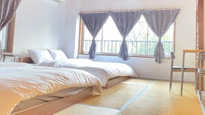 Una habitación con cama, una mesita y una ventana con cortinas.