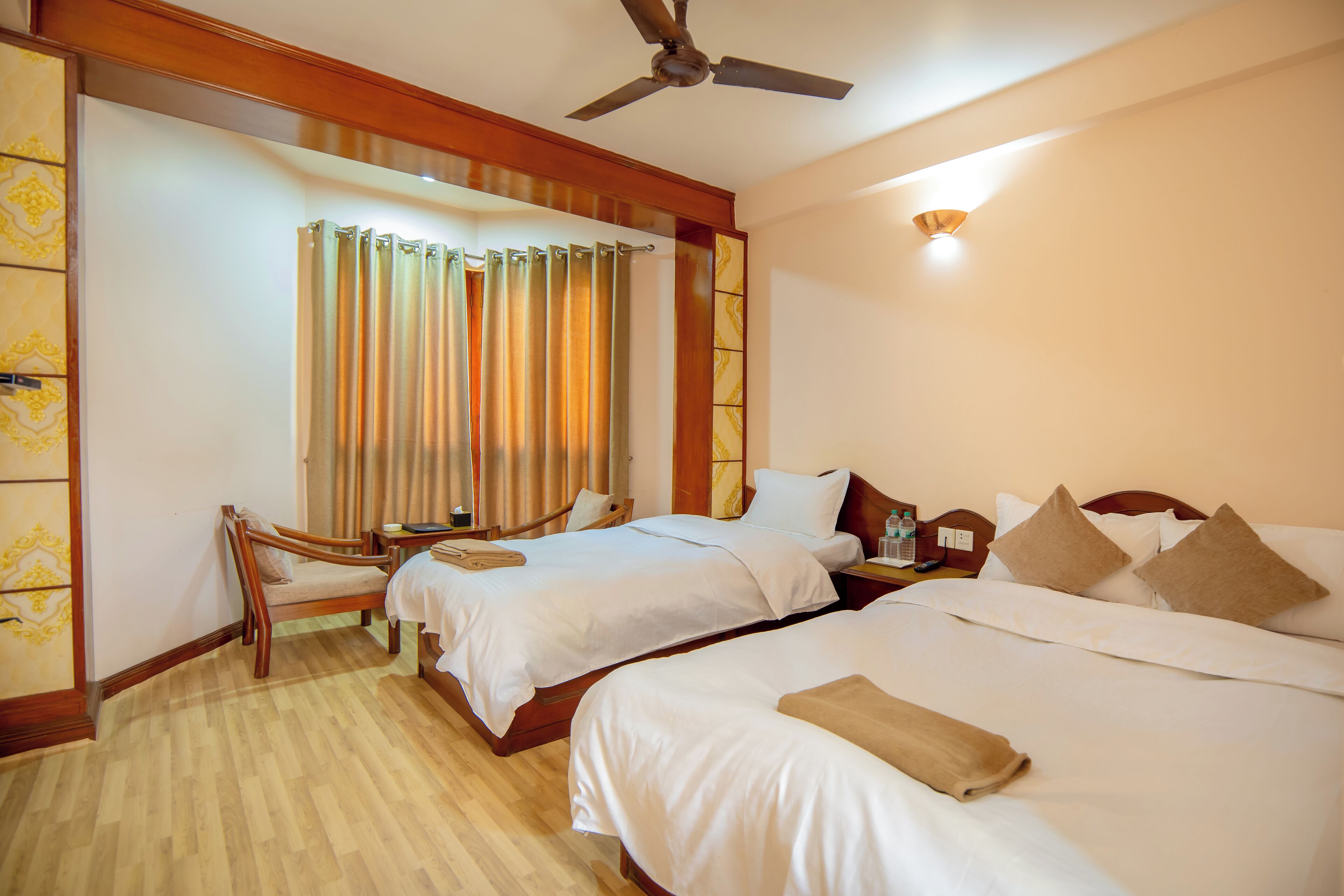 A hotel room with two beds, a wooden chair, a nightstand, and a ceiling fan.