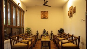 A dining area with wooden chairs and a table, a ceiling fan, and decorative wall art. - Laavanya Inn (Pokhara)