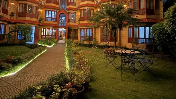 A multi-story hotel with a central courtyard, surrounded by lush greenery and potted plants. - Laavanya Inn (Pokhara)