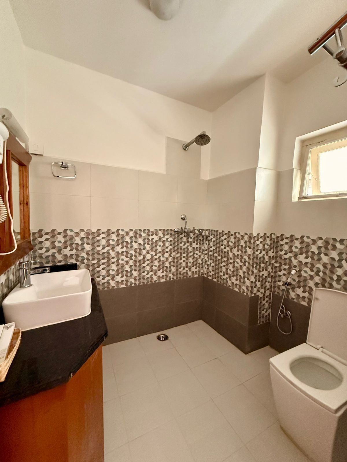 Bagno con lavandino, WC, doccia e finestra.