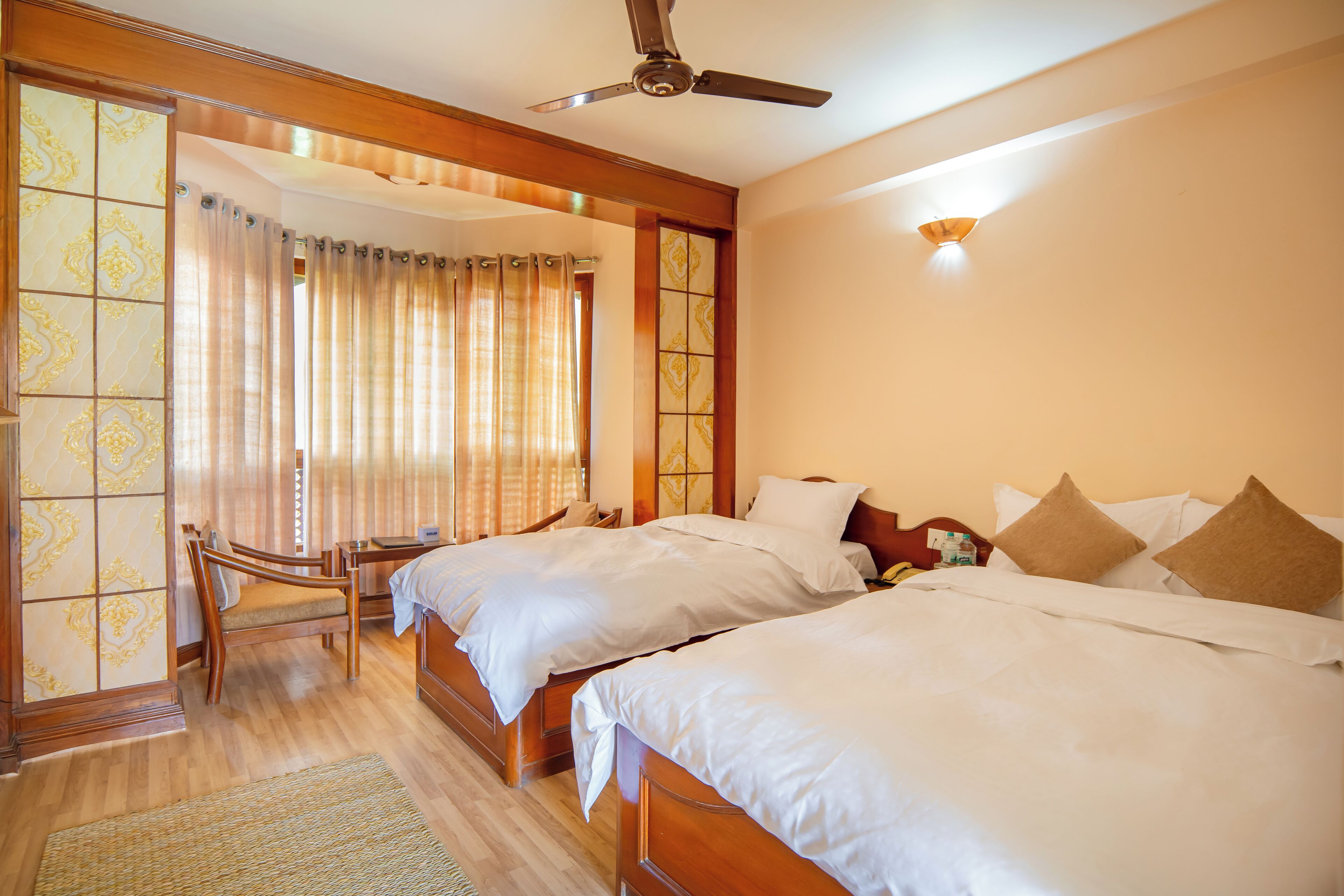 Une chambre d’hôtel avec deux lits, un ventilateur de plafond et une porte coulissante avec des rideaux.