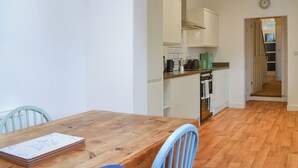 Una cocina con armarios blancos, una mesa de madera y una silla azul.