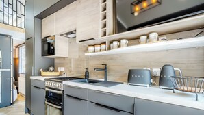 A modern kitchen with grey cabinetry, a stainless steel range, a built-in oven, a black coffee machine, and a kettle on the countertop. - 2 bedroom accommodation in Chirk, near Llangollen (Chirk, near Llangollen)