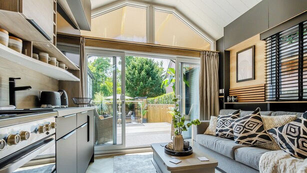 A modern kitchen with a built-in oven and a dining area with a sofa and a coffee table. - 2 bedroom accommodation in Chirk, near Llangollen (Chirk, near Llangollen)