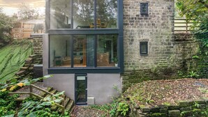 A modern two-story building with large windows, a stone facade, and a small window on the upper floor.